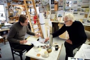 Lars Jönses och Gösta Backlund i samspråk om "Papper i långa banor", det verk som under många år smyckade en transportgång på Kvarnsvedens pappersbruk. Nu är både gången och konstverket borta.
